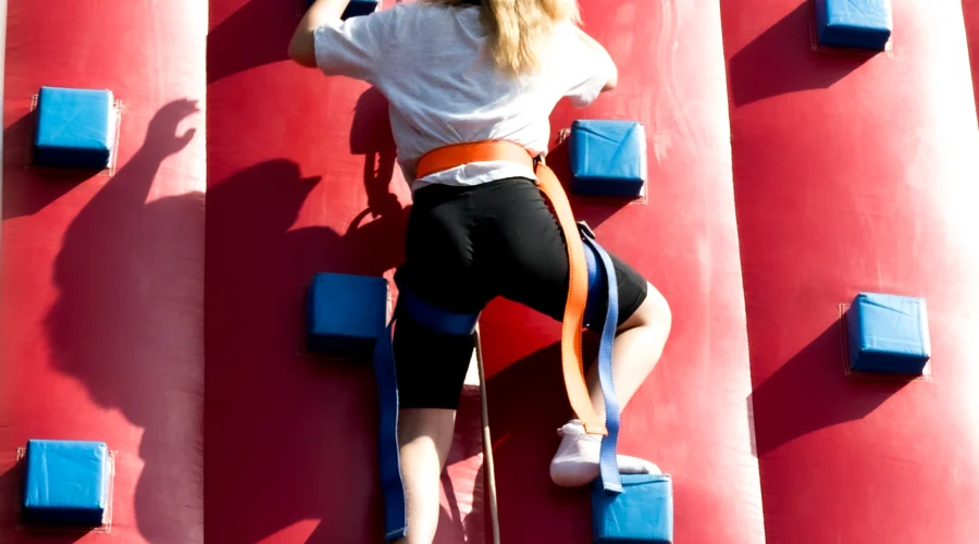 A woman climbing up a climbing wall